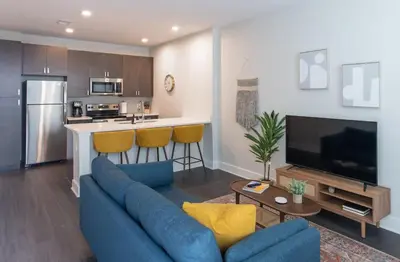 a living room with a blue couch and a kitchen at CozySuites at ArtCincy in Cincinnati