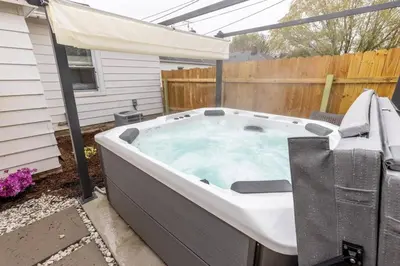 a hot tub in a backyard with an umbrella at Quiet Modern Home w/ Hot Tub! in Parma