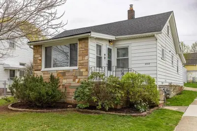 a white house with some bushes in the yard at Quiet Modern Home w/ Hot Tub! in Parma