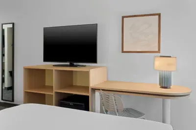 a room with a tv and a desk with a lamp at Spark By Hilton Newcomerstown in Newcomerstown