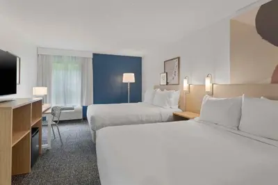 a hotel room with two beds and a flat screen tv at Spark By Hilton Newcomerstown in Newcomerstown