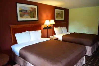 two beds in a hotel room with two lamps at Greystone Motel in Hillsboro