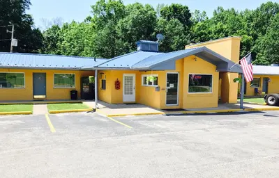 a yellow building with a flag in a parking lot at Greystone Motel in Hillsboro