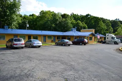 a yellow building with cars parked in a parking lot at Greystone Motel in Hillsboro
