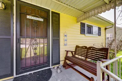 a wooden bench sitting on the porch of a yellow house at Pet-Friendly Ohio Escape with Deck and Community Dock! in Celina