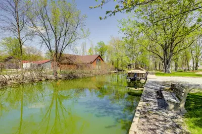 a river with a house and a boat in it at Pet-Friendly Ohio Escape with Deck and Community Dock! in Celina