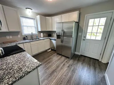 a kitchen with a stainless steel refrigerator and wooden floors at Suite 1 in Butler
