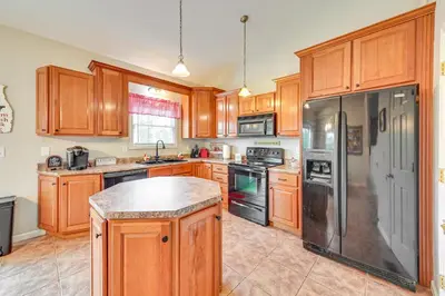 a kitchen with wooden cabinets and a black refrigerator at Home with Private Pool - 15 miles to Ark Encounter! in Berry