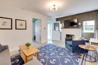a living room with a blue couch and a fireplace at Walk to Lake Nautical Akron Cottage with Deck! in Uniontown