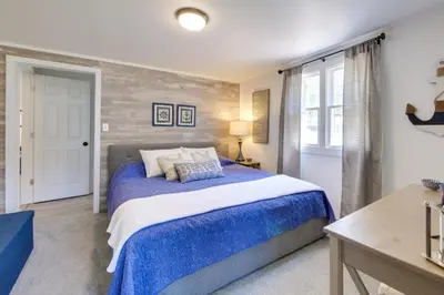 a bedroom with a bed with a blue comforter at Walk to Lake Nautical Akron Cottage with Deck! in Uniontown