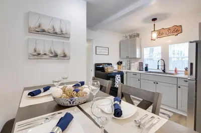 a kitchen and dining room with a table with wine glasses at Walk to Lake Nautical Akron Cottage with Deck! in Uniontown