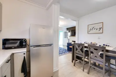 a kitchen and dining room with a refrigerator and a table at Walk to Lake Nautical Akron Cottage with Deck! in Uniontown