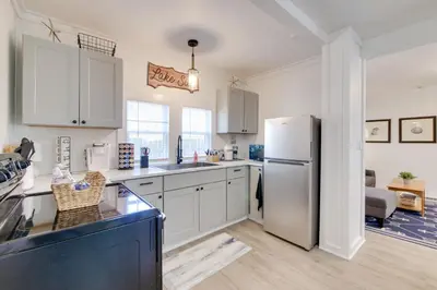 a kitchen with white cabinets and a refrigerator at Walk to Lake Nautical Akron Cottage with Deck! in Uniontown