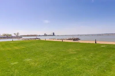 a grassy field next to a beach with a body of water at Waterfront Sandusky Vacation Rental Downtown! in Sandusky
