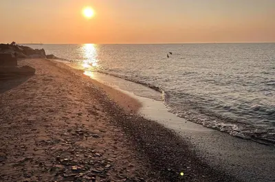 a beach at sunset with a person in the water at Recharge & Reconnect Your cozy Vermilion nest in Vermilion