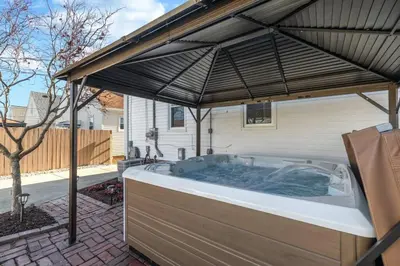 a hot tub under an umbrella in a backyard at Parma Home w/ Hot Tub and Arcade room! in Parma
