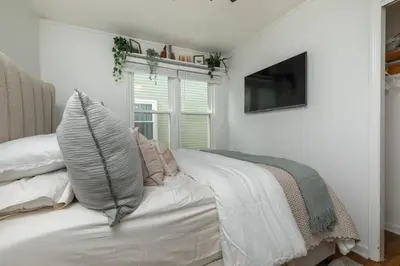 a white bed with pillows and a television in a room at Parma Home w/ Hot Tub and Arcade room! in Parma
