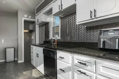 a kitchen with white cabinets and black appliances at Parma Home w/ Hot Tub and Arcade room! in Parma