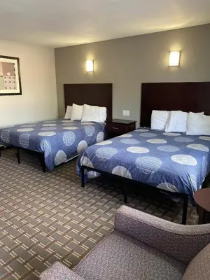 a hotel room with two beds and a chair at New Budget Inn in Eaton
