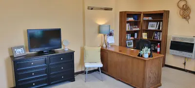 a room with a desk with a television and a chair at Upstage Stay in Bainbridge