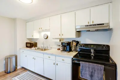 a kitchen with white cabinets and a black stove at Cozy Norwalk Apt Near Cedar Point and Kalahari! in Norwalk
