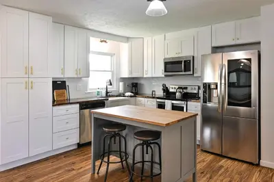a kitchen with white cabinets and a stainless steel refrigerator at 3BR Home for 8 - Only 5 Minutes to Ark - Foosball in Williamstown