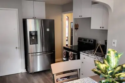 a kitchen with a stainless steel refrigerator and white cabinets at Beautiful 4 bedroom in Cleveland in Euclid