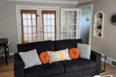 a living room with a black couch with pillows at Beautiful 4 bedroom in Cleveland in Euclid