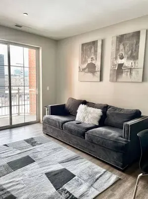 a black leather couch in a living room with a window at The KING Apt in Downtown Columbus in Columbus