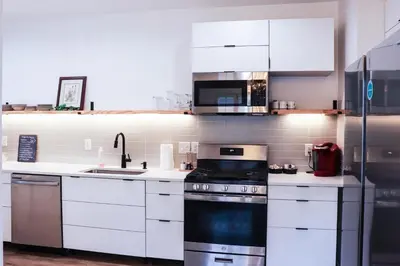 a kitchen with white cabinets and a stove top oven at Downtown Retreat - 2BR Oasis in Columbus