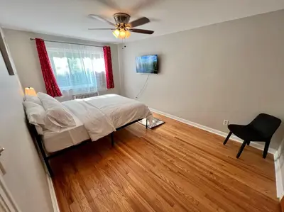 a bedroom with a bed and a fan and a chair at Red Ruby Spacious 2 Bedroom Apt 10 Minutes to Dwntwn in Cincinnati