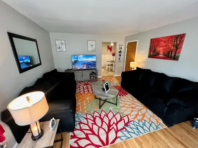 a living room with a black couch and a table at Red Ruby Spacious 2 Bedroom Apt 10 Minutes to Dwntwn in Cincinnati