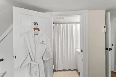 a white robe hanging on a door in a bathroom at The Luxe/Hot Tub/12min to Horse Park/30 Min to Ark in Georgetown