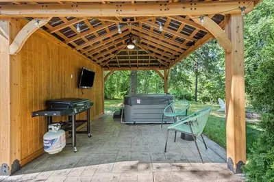 a patio with a wooden pergola and a grill at The Luxe/Hot Tub/12min to Horse Park/30 Min to Ark in Georgetown