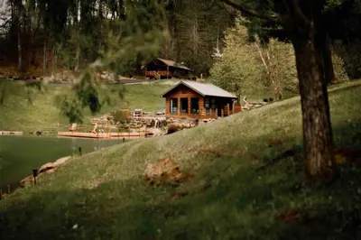 a log cabin on a hill next to a lake at Lake with Dock and Hot Tub Hocking Hills Cabin in Rockbridge