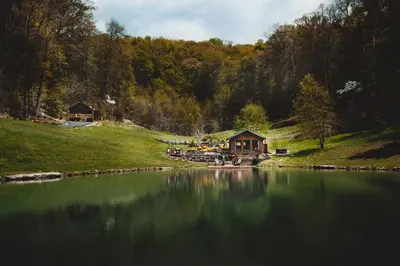 a house sitting on the side of a lake at Lake with Dock and Hot Tub Hocking Hills Cabin in Rockbridge