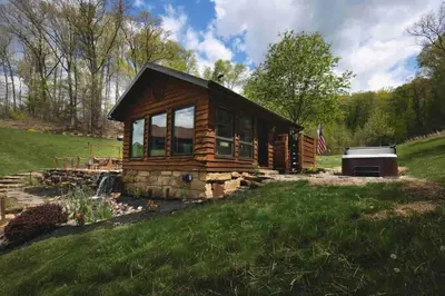a log cabin with a stove in a field at Lake with Dock and Hot Tub Hocking Hills Cabin in Rockbridge