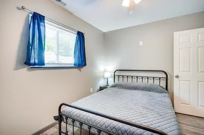 a bedroom with a bed and a window with blue curtains at Zanesville Vacation Rental 2 Mi to Downtown! in Zanesville