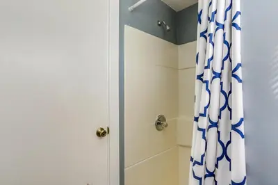 a bathroom with a shower with a blue and white shower curtain at Dog-Friendly Port Clinton Home Walk to Lake Erie! in Port Clinton