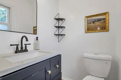 a bathroom with a sink and a toilet and a mirror at Housepitality - Electric Ave - 3 BDR and Hot Tub in Westerville
