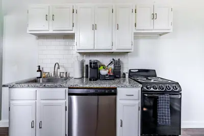 a kitchen with white cabinets and a stainless steel dishwasher at Jungle House Columbus Downtown Free Parking Sleeps 6 - Steps to Convention Center & Nationwide Arena - 1BR Short North Luxury Home - Over 5,800 Five Star Stays in Columbus