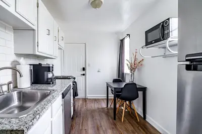 a kitchen with white cabinets and a sink and a table at Jungle House Columbus Downtown Free Parking Sleeps 6 - Steps to Convention Center & Nationwide Arena - 1BR Short North Luxury Home - Over 5,800 Five Star Stays in Columbus