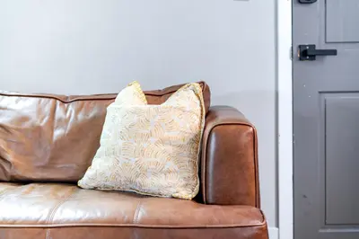 a pillow sitting on top of a brown leather couch at Jungle House Luxury Stays - Columbus Downtown Short North in Columbus