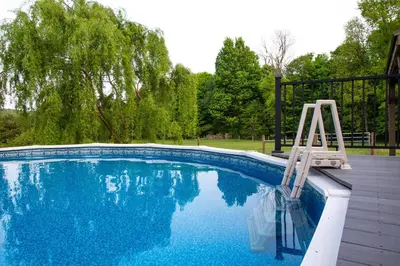 a swimming pool with a chair sitting next to it at Maple Retreat with Big Pool in Dundee