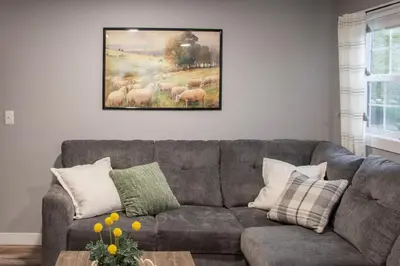 a living room with a couch and a painting of sheep at Haven on 41 in Warsaw