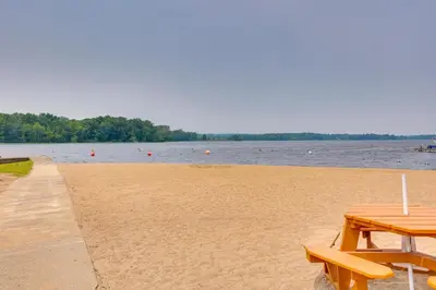 a picnic table sitting on a beach next to the water at Chippewa Lake Cottage with Fire Pit! in Chippewa Lake