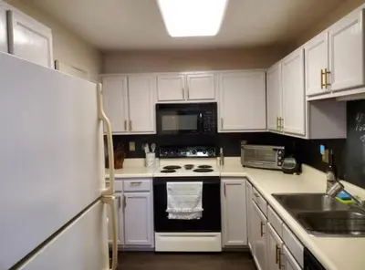 a kitchen with white cabinets and a black stove top oven at The Redhawk Hideaway: Charming 2BR Condo near Miami Univ in Oxford! Book now! in Oxford