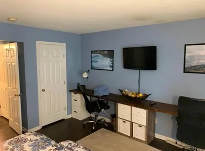 a room with a desk and a television on a blue wall at The Redhawk Hideaway: Charming 2BR Condo near Miami Univ in Oxford! Book now! in Oxford