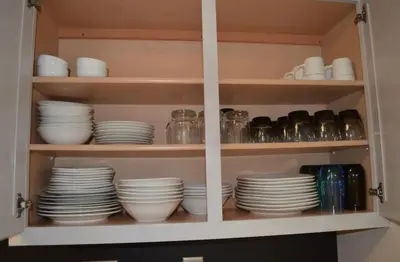 a cabinet filled with plates and cups and dishes at The Redhawk Hideaway: Charming 2BR Condo near Miami Univ in Oxford! Book now! in Oxford