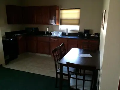 a kitchen with wooden cabinets and a table and chairs at Pacer Inn & Suites Motel in Delaware